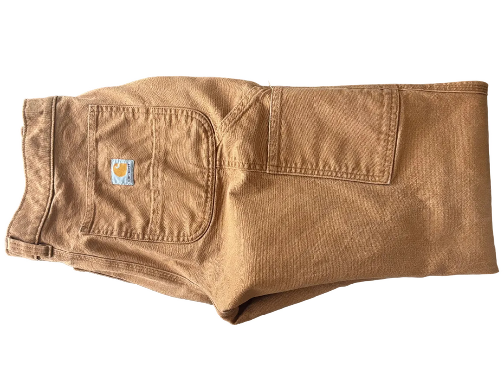 Folded brown pants with a brand logo on a dark surface
